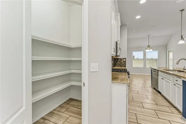 a large kitchen with granite countertop a large counter top space a sink stainless steel appliances and cabinets