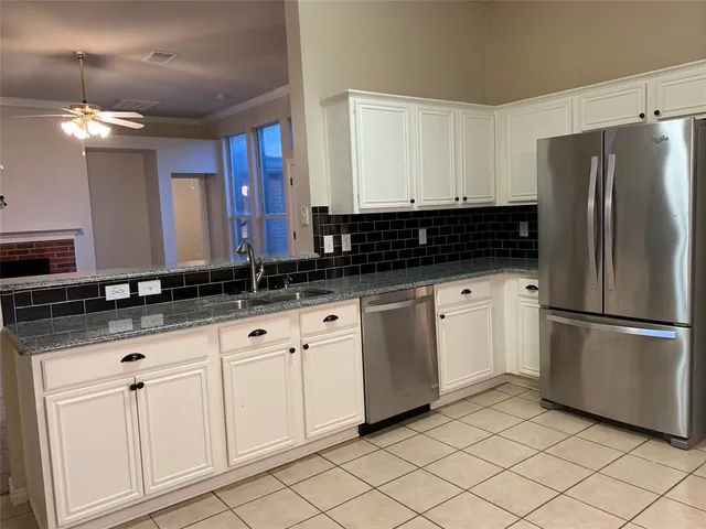 a kitchen with granite countertop white cabinets and stainless steel appliances
