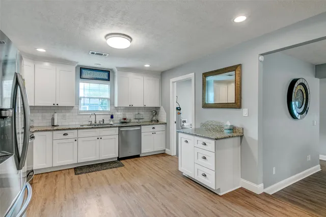 a kitchen with stainless steel appliances granite countertop a stove a sink dishwasher and a refrigerator with wooden floor