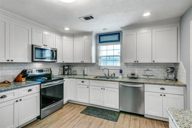 a kitchen with cabinets stainless steel appliances a sink and a window