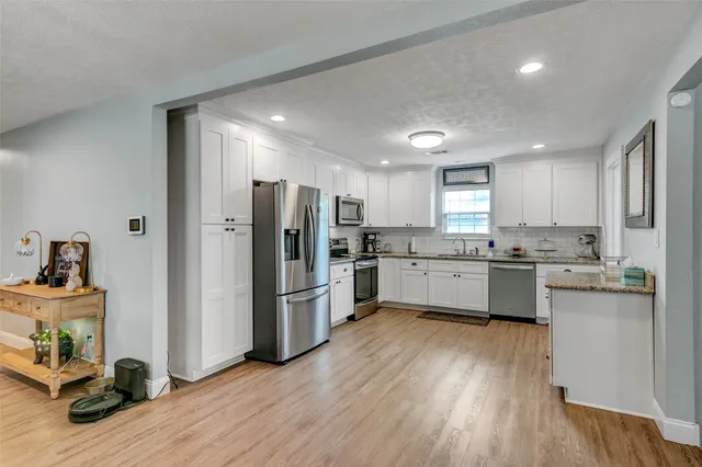 a kitchen with refrigerator a sink and wooden floor