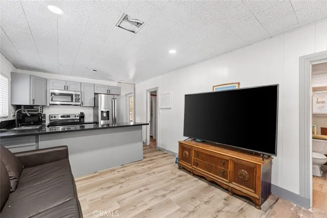 a living room with stainless steel appliances kitchen island furniture and a flat screen tv