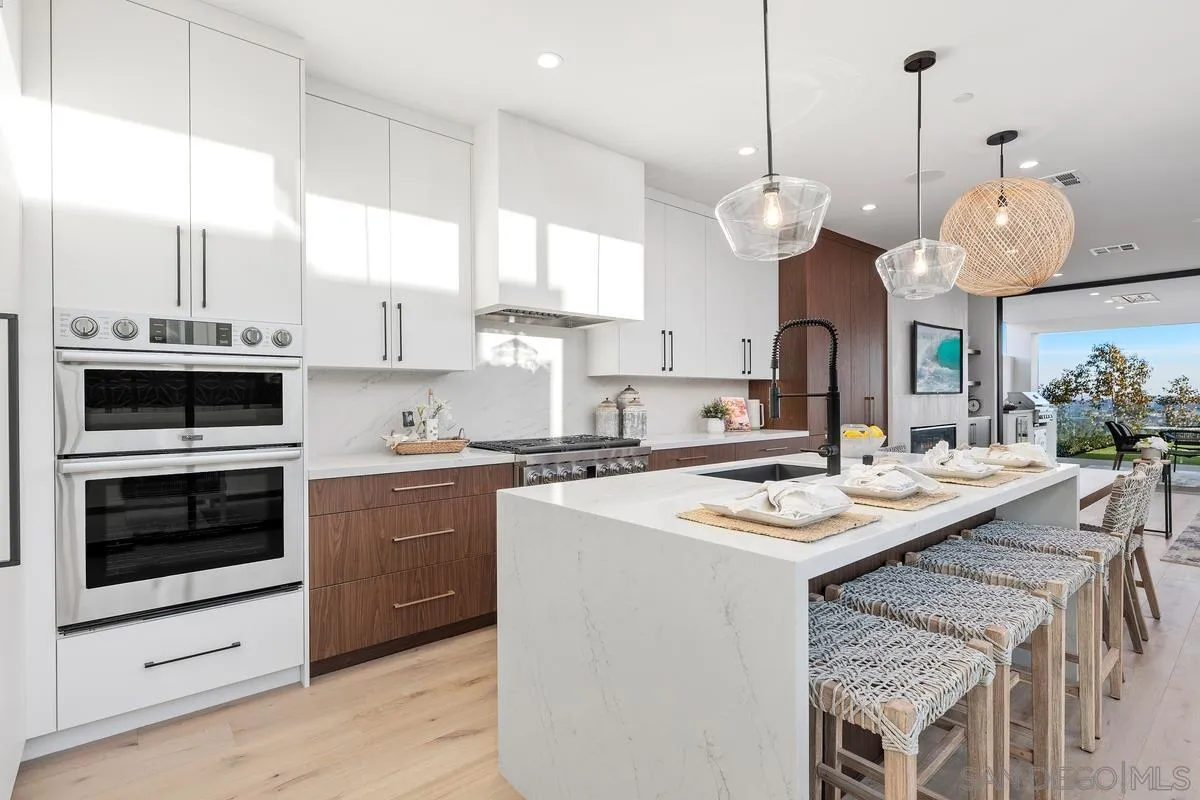 1237 Van Nuys Street San Diego, CA 92109 - Photo 6 of 32 a kitchen with a stove a microwave a sink a dining table and chairs