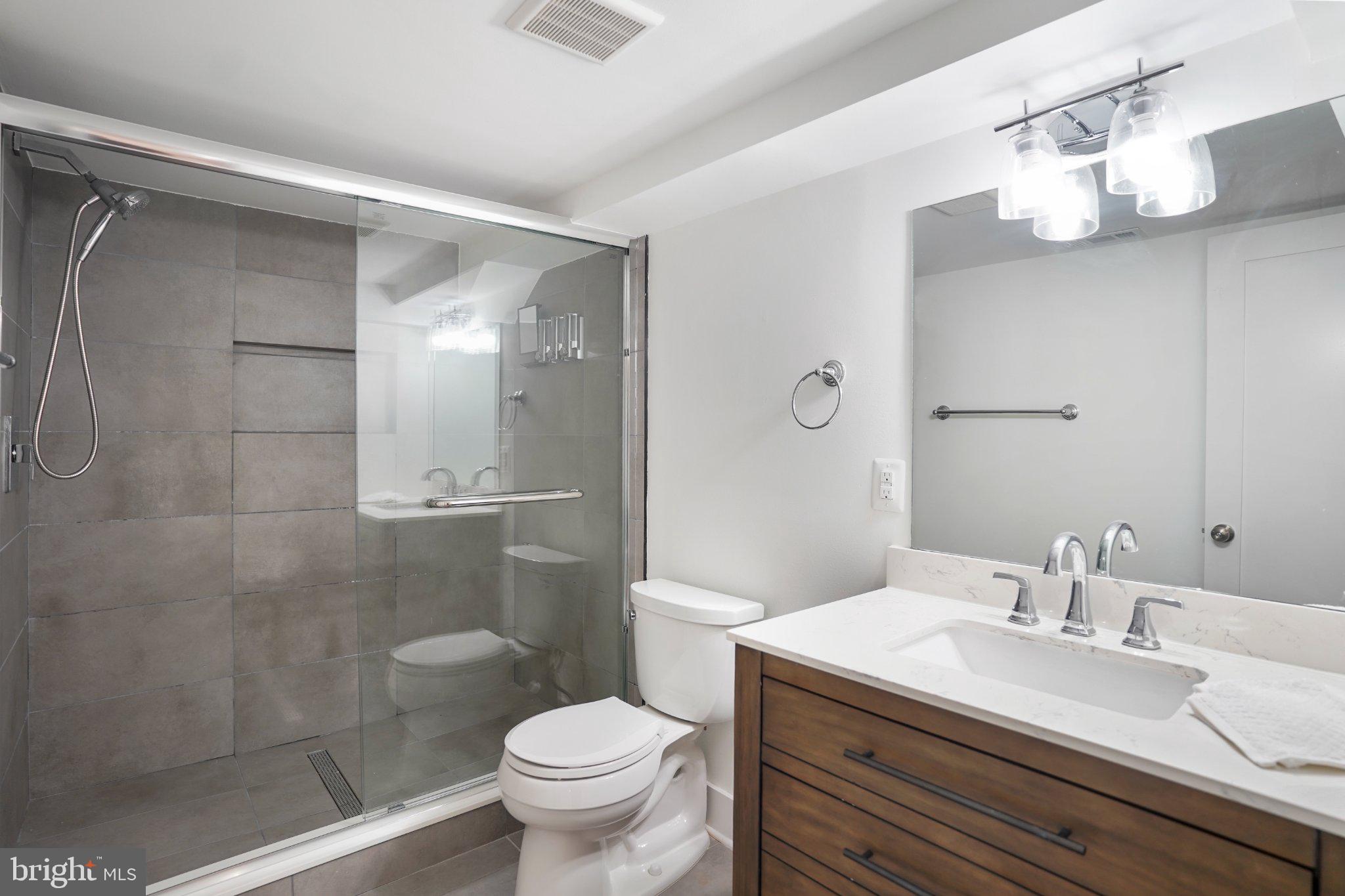 112 V Street Northeast Washington, DC 20002 - Photo 14 of 25 a bathroom with a granite countertop sink a toilet a mirror and shower