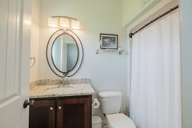 a bathroom with a granite countertop toilet sink and mirror