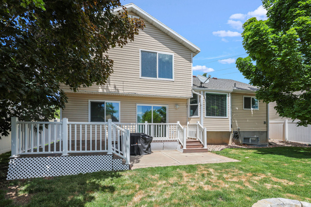 142 East 2675th Street South Clearfield, UT 84015 - Photo 35 of 49 Expansive backyard featuring a wood-finish deck with white railing, a concrete patio, and a verdant lawn