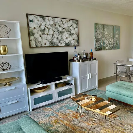 a living room with stainless steel appliances kitchen island granite countertop furniture and a rug