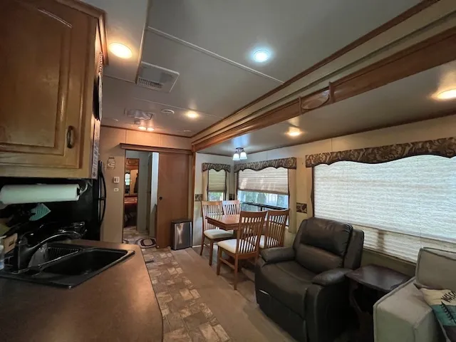 a living room with furniture a flat screen tv and kitchen view