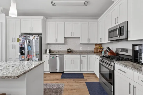 a kitchen with stainless steel appliances granite countertop a stove top oven a refrigerator a sink and dishwasher with wooden floor