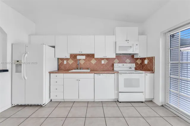 a kitchen with white cabinets a sink and appliances
