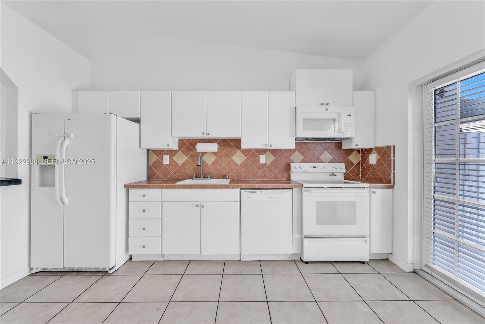 7665 Northwest 183rd Terrace, Unit 1405 Hialeah, FL 33015 - Photo 6 of 26 a kitchen with white cabinets a sink and appliances