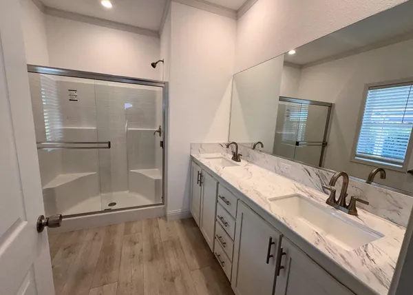 a bathroom with a double vanity sink mirror and shower