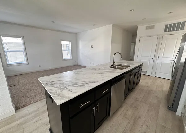 a kitchen with granite countertop kitchen island stainless steel appliances a sink stove and wooden floor