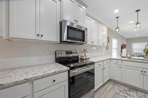 a kitchen with granite countertop a sink cabinets and wooden floor
