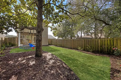 a view of a backyard with a tree and wooden fence