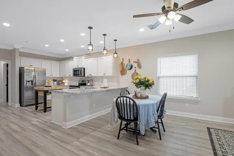 a kitchen with kitchen island a dining table chairs stainless steel appliances and cabinets