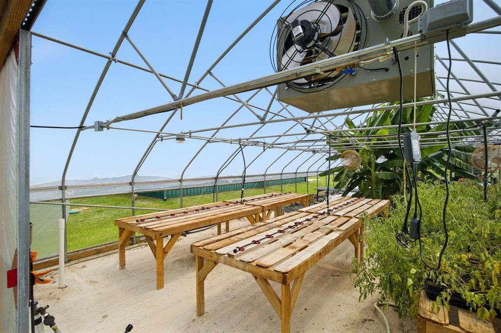 4020 Farm To Market 515 Emory, TX 75440 - Photo 7 of 39 Production-ready greenhouse equipped with commercial wall-mounted exhaust fan for temperature and humidity control, drip-irrigated wooden grow benches, overhead lighting, and thriving plantings — ready to scale from day one