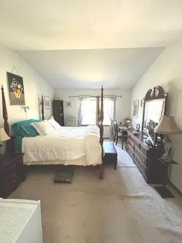 a large bedroom with a bed a mirror and lamp