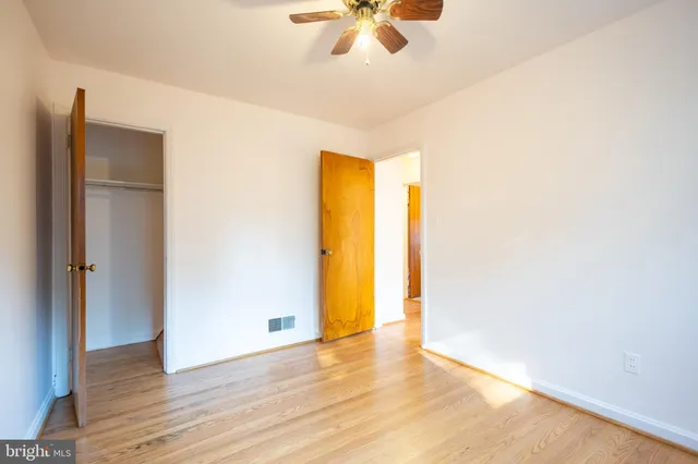 a view of an empty room with a ceiling fan and wooden floor