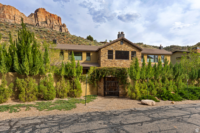 105 River Bend Circle, Unit 105 Springdale, UT 84767 - Photo 1 of 56 Stone and stucco exterior featuring multiple windows, a prominent iron gate entrance, and mature landscaping