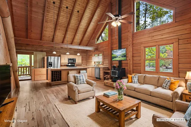 a living room with furniture a ceiling fan and a large window