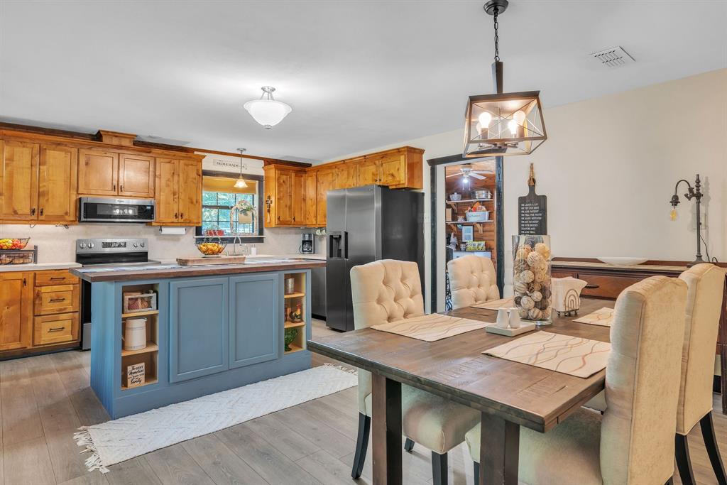 860 County Road 1627 Rusk, TX 75785 - Photo 7 of 37 a open kitchen with stainless steel appliances granite countertop a stove top oven a refrigerator a sink dishwasher a dining table and chairs with wooden floor
