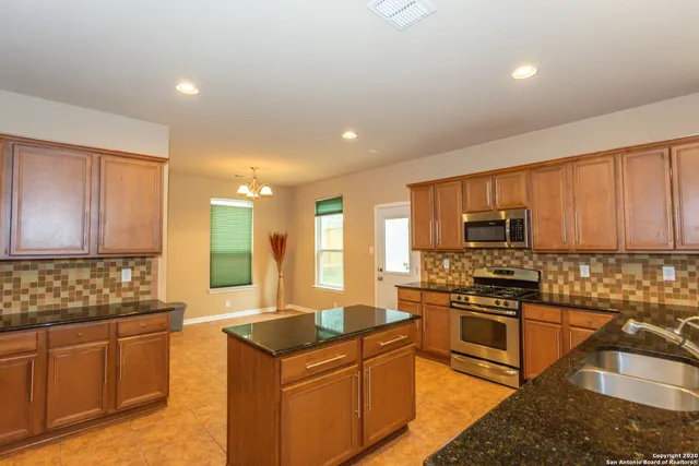 a kitchen with stainless steel appliances granite countertop a stove a sink and a microwave