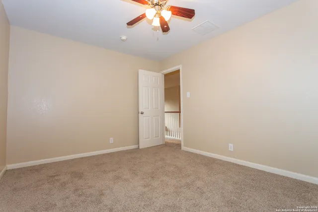 an empty room with chandelier fan and windows