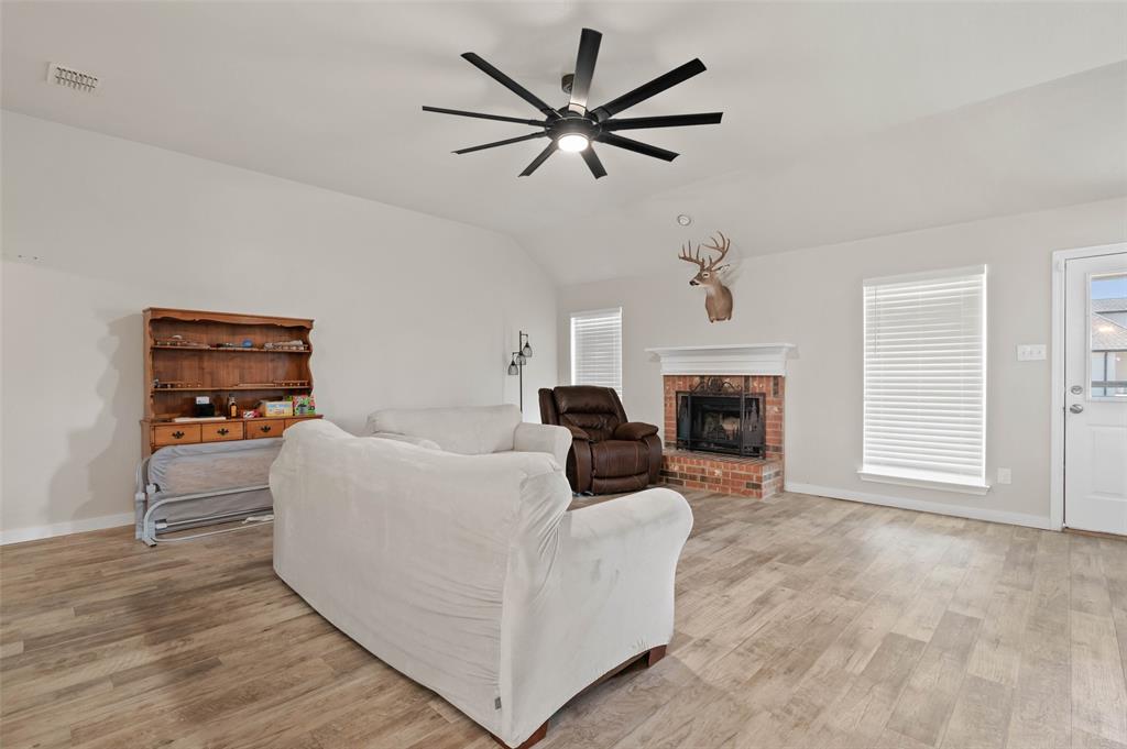 107 High View Court Decatur, TX 76234 - Photo 5 of 9 Living area with light wood-type flooring, a ceiling fan, a fireplace, and vaulted ceiling