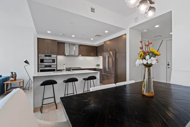 a kitchen with stainless steel appliances granite countertop a refrigerator a stove a sink dishwasher and microwave with wooden floor