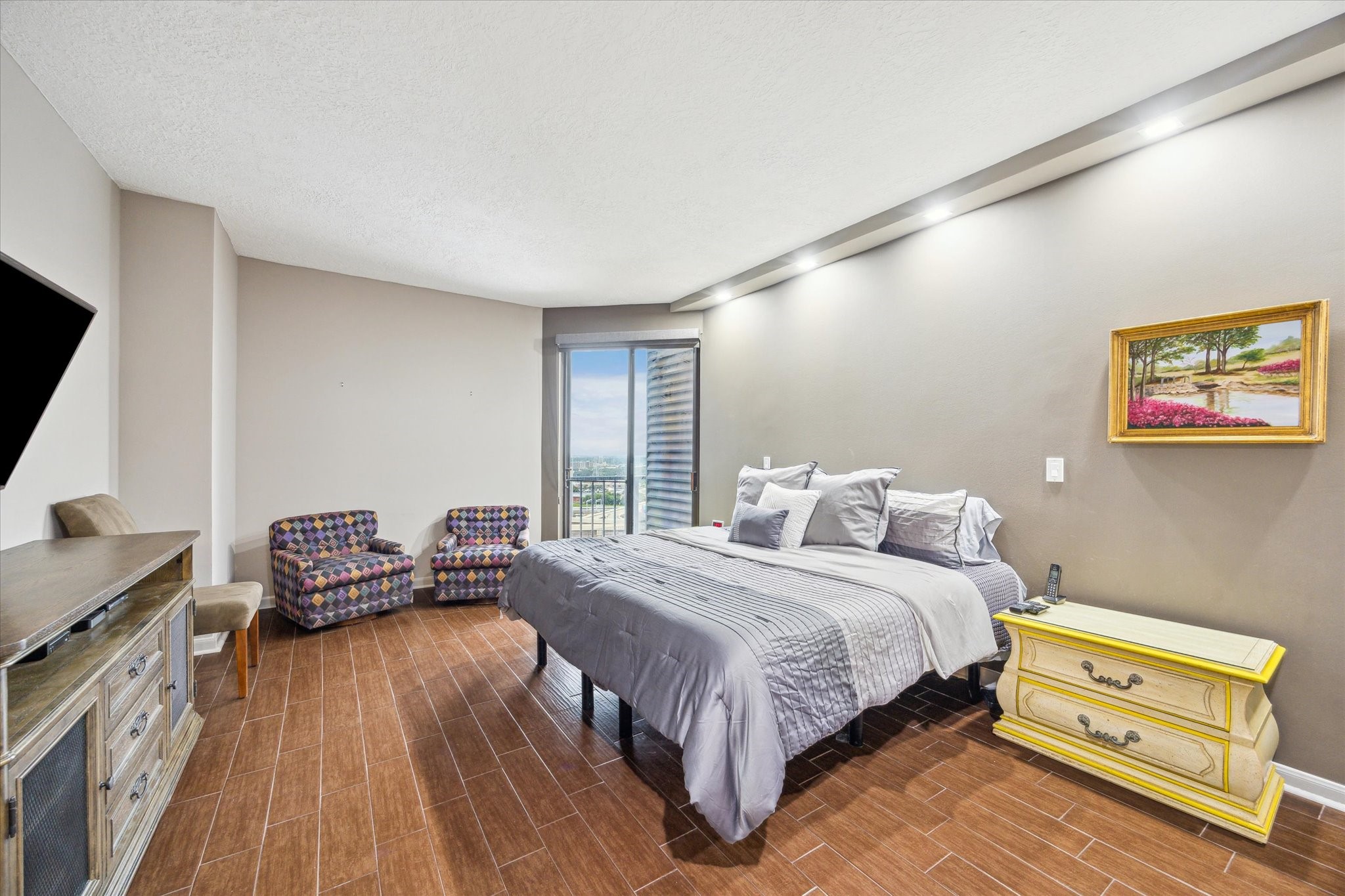 3350 McCue Road, Unit 1504 Houston, TX 77056 - Photo 14 of 32 The spacious primary bedroom boasts sleek tile flooring and art lighting, with room for a seating area. A sliding door opens to a charming Juliet-style balcony, while the luxurious ensuite bath completes this serene retreat.