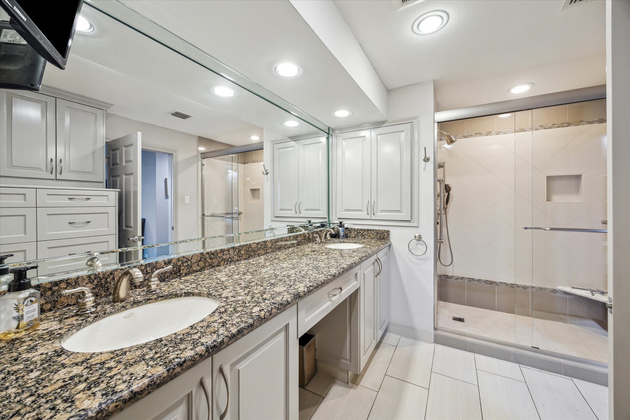 3350 McCue Road, Unit 1504 Houston, TX 77056 - Photo 15 of 32 The primary bath offers dual sinks set in granite countertops, generous vanity space, recessed lighting, a spacious glass-enclosed shower, and built-in cabinets for additional storage.