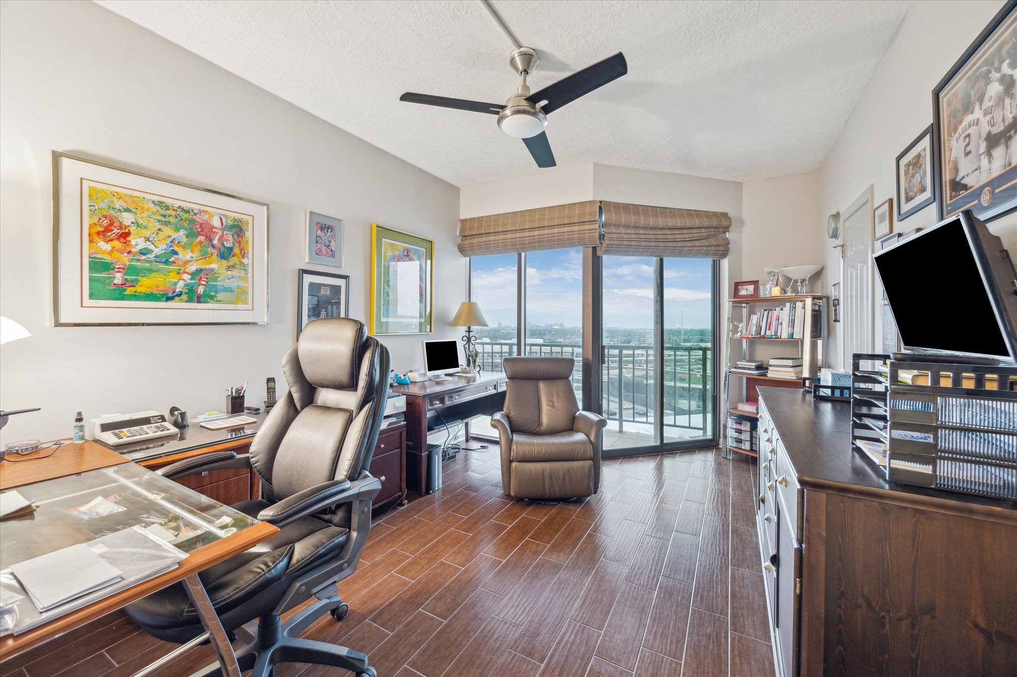 3350 McCue Road, Unit 1504 Houston, TX 77056 - Photo 18 of 32 Currently serving as a stylish office, this secondary bedroom boasts large sliding doors that open onto the balcony, sleek tile flooring, and a ceiling fan with integrated lighting.