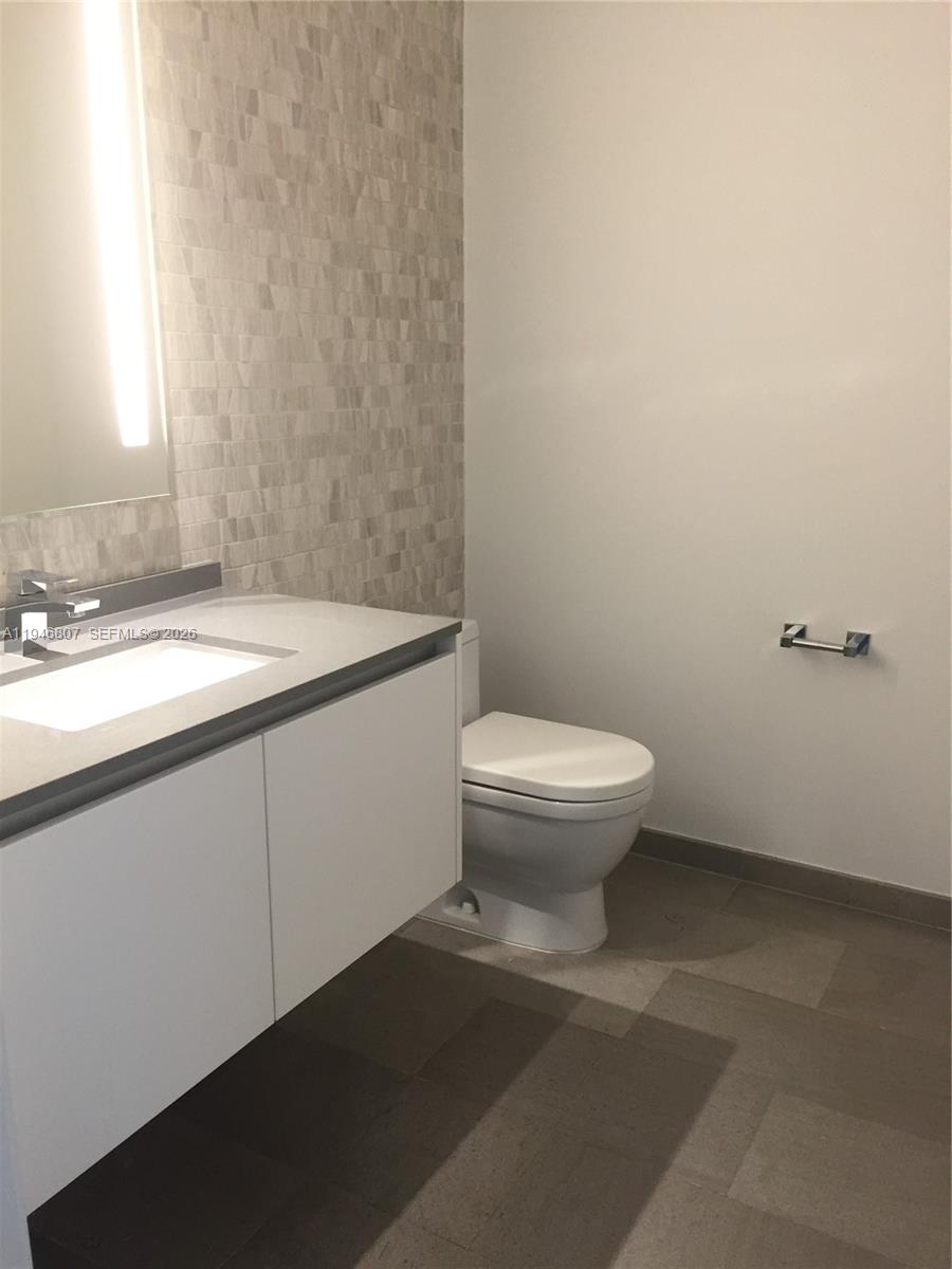 68 Southeast 6th Street, Unit 2504 Miami, FL 33131 - Photo 17 of 47 a bathroom with a granite countertop toilet and a sink