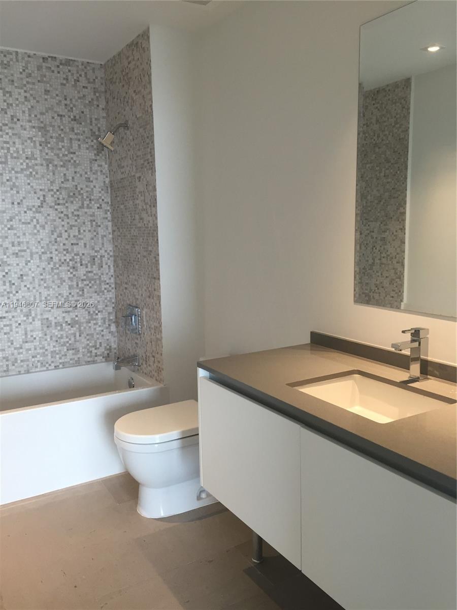 68 Southeast 6th Street, Unit 2504 Miami, FL 33131 - Photo 19 of 47 a bathroom with a granite countertop sink and a bathtub