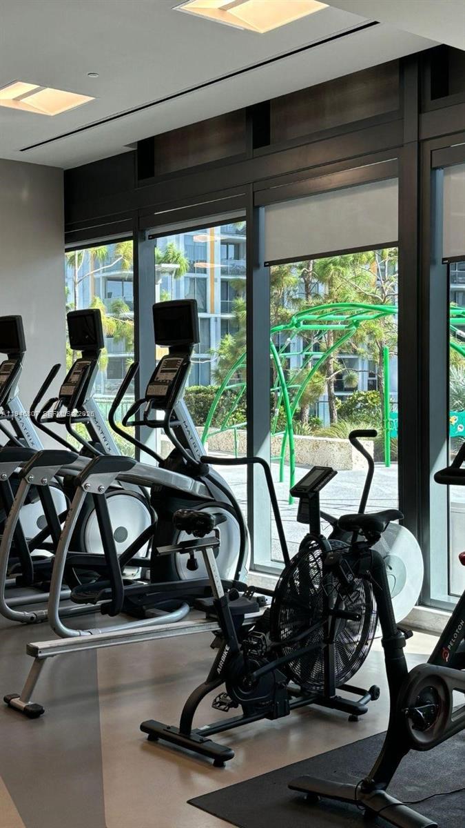 68 Southeast 6th Street, Unit 2504 Miami, FL 33131 - Photo 41 of 47 a room with gym equipment and a large window