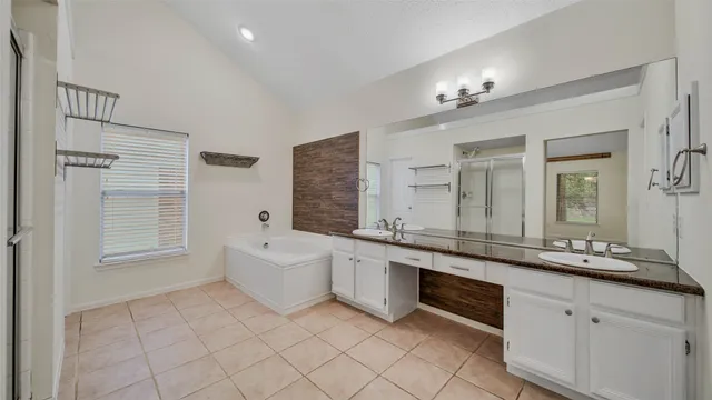 a large bathroom with a granite countertop double vanity sink a mirror and a bathtub