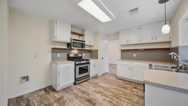 a kitchen with stainless steel appliances granite countertop a sink a stove a refrigerator and white cabinets
