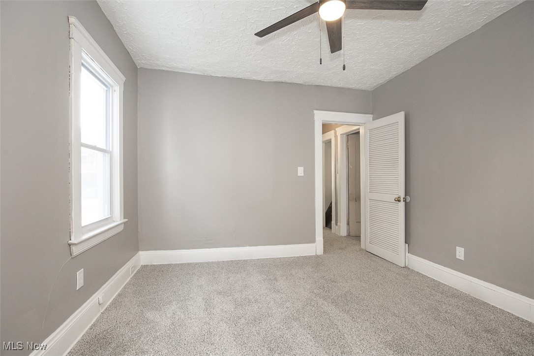 1045 Carlyon Road Cleveland, OH 44112 - Photo 19 of 26 Empty room with light carpet, healthy amount of natural light, ceiling fan, and a textured ceiling