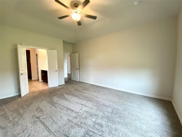 a view of an empty room and chandelier fan
