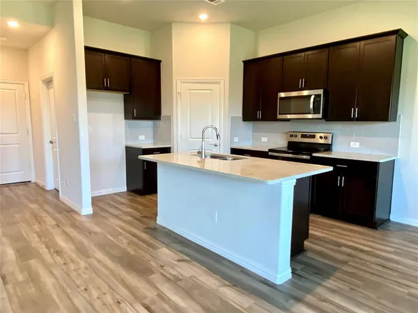 a kitchen with stainless steel appliances granite countertop a sink a stove top oven a counter space and cabinets