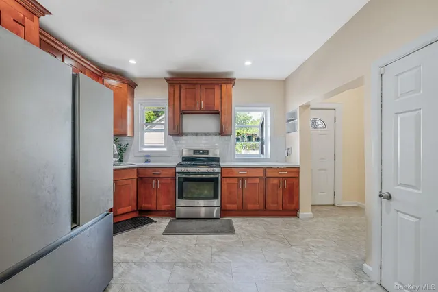 a large kitchen with stainless steel appliances granite countertop a stove a sink and a refrigerator