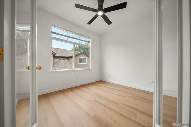 a view of empty room with wooden floor and fan