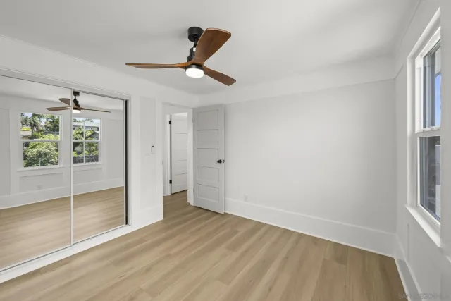 a view of empty room with wooden floor and fan