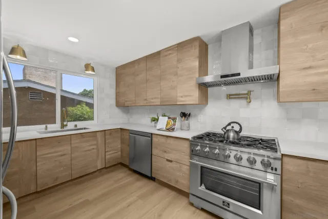 a kitchen with stainless steel appliances granite countertop a sink a stove and a wooden floors