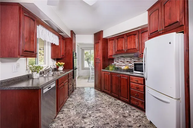 a kitchen with stainless steel appliances granite countertop a refrigerator a stove and a wooden cabinets