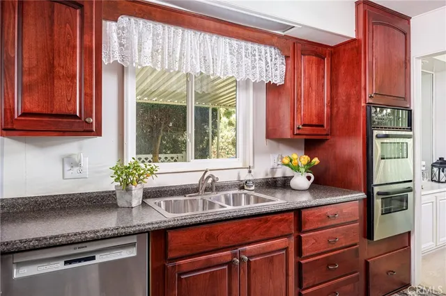 a kitchen with stainless steel appliances granite countertop a sink a counter space and windows