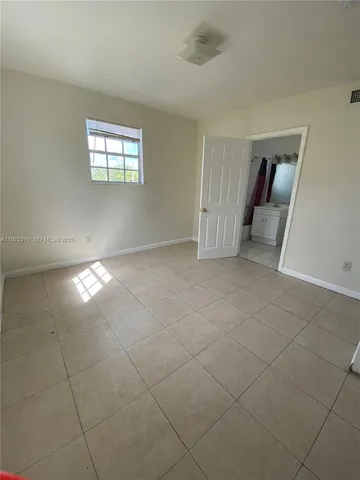 a view of an empty room with glass door and bathroom