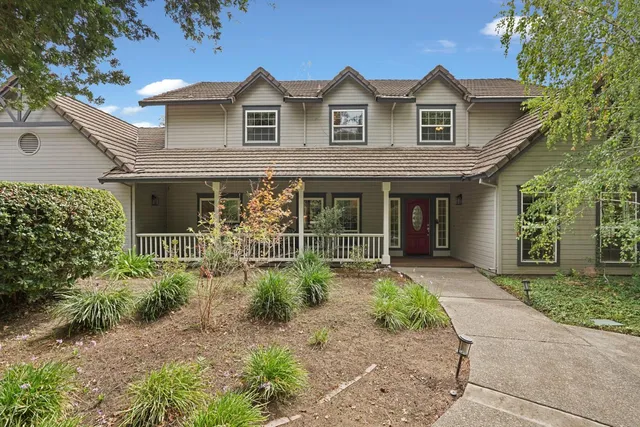 a front view of a house with garden and trees