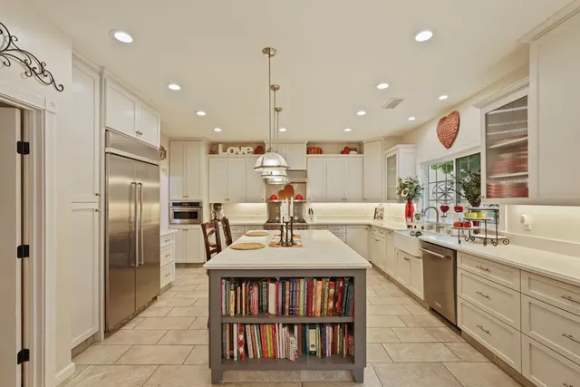 a large kitchen with kitchen island a large counter top a sink a stove and a large window